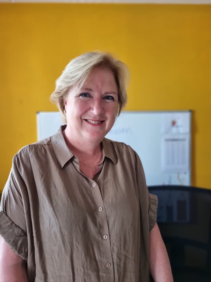 Ina schrijft met een pen aan haar werktafel in de leerstudio.