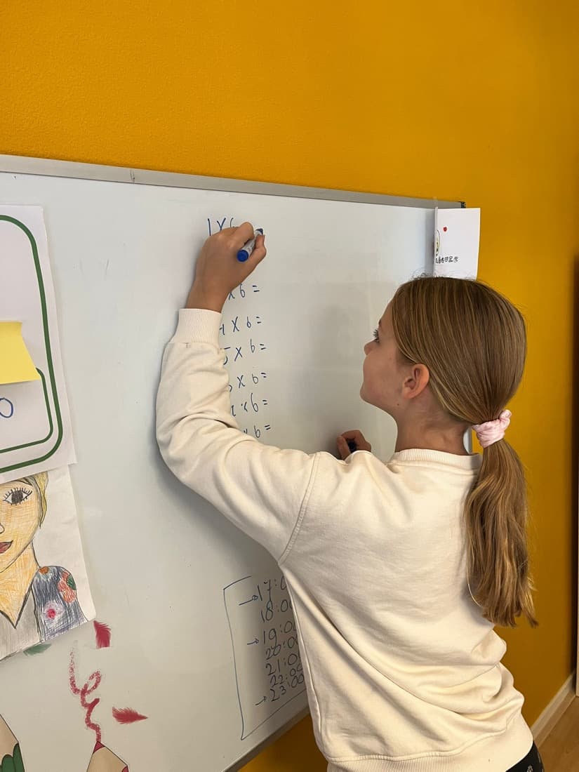 Een meisje schrijft de tafel van zes op het whiteboard in de leerstudio.